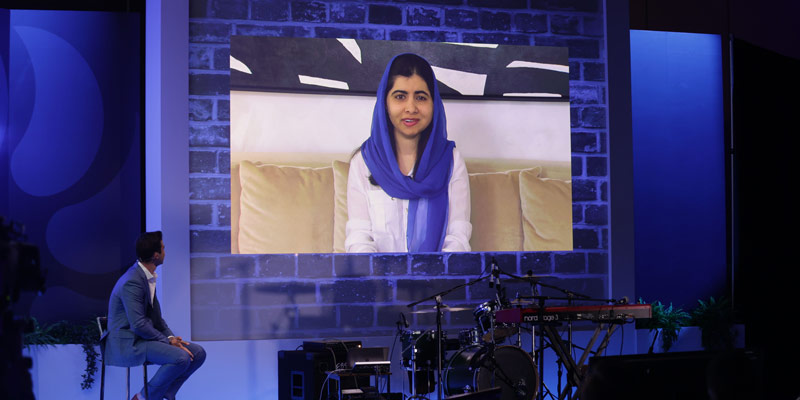 malala yousafzai as a speaker onstage on a screen at hybrid event